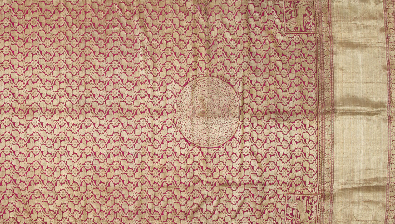 A saree heavily brocaded in gold with a jaali or trellis pattern that covers its length and a large medallion towards the border.