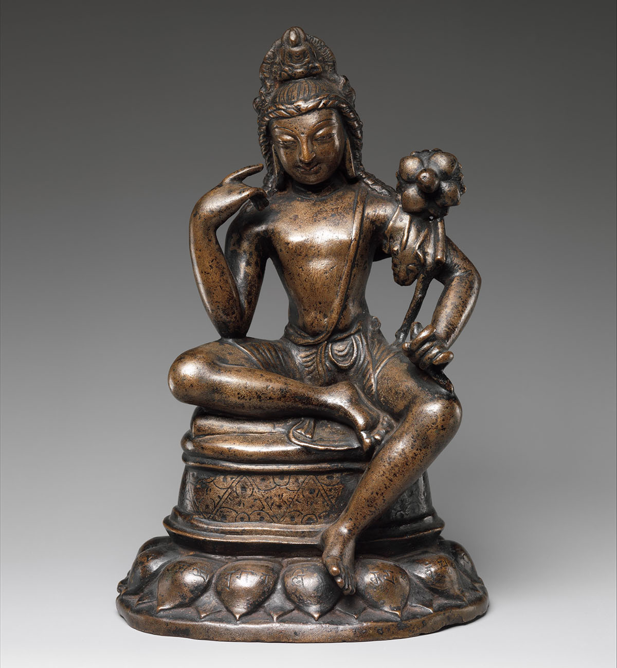 A bronze statue depicting Avalokiteshvara Padmapani, seated with the left leg hanging down.