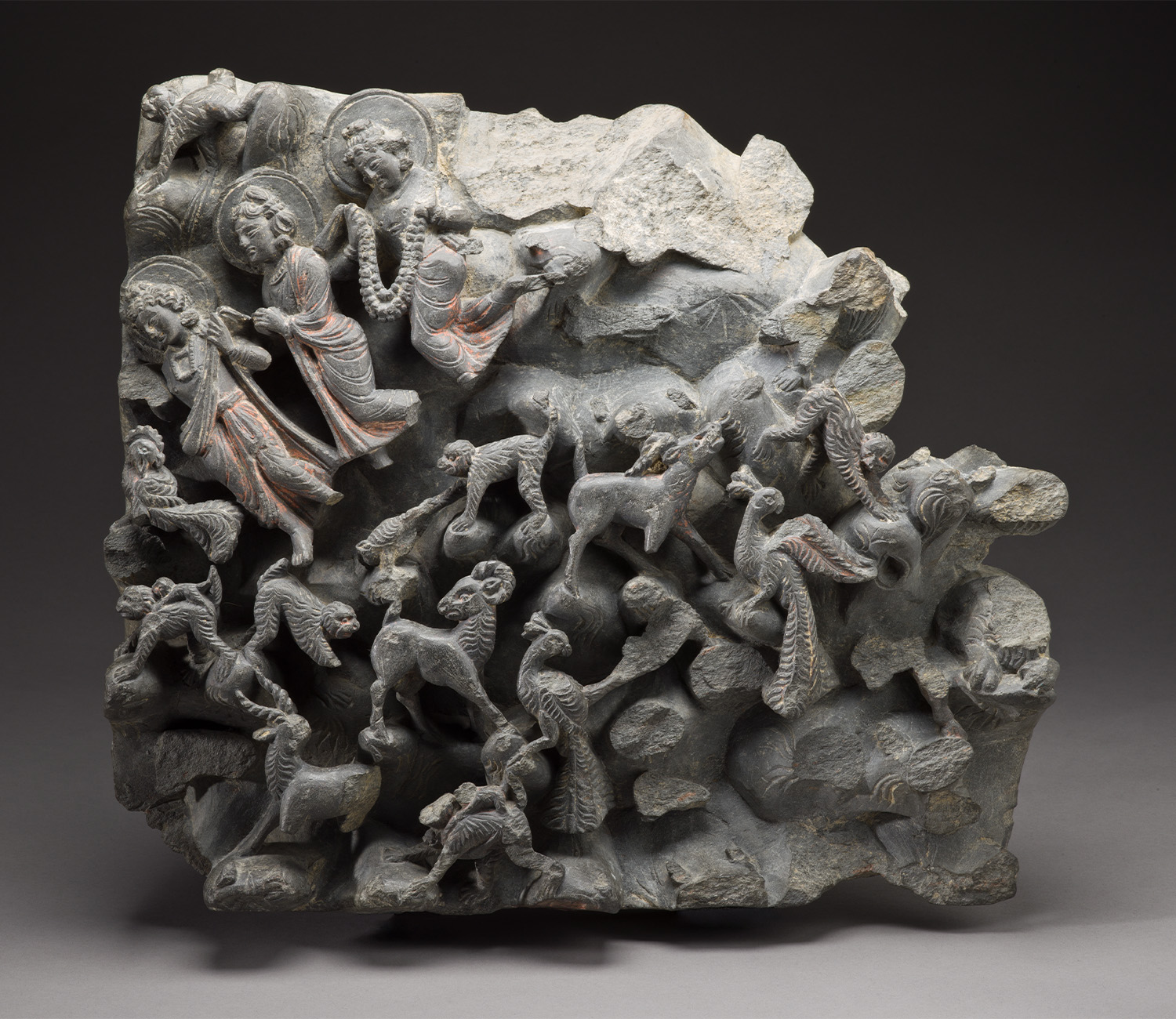 A fragment of a stone relief depicting three gods on the top left and animals on the bottom.