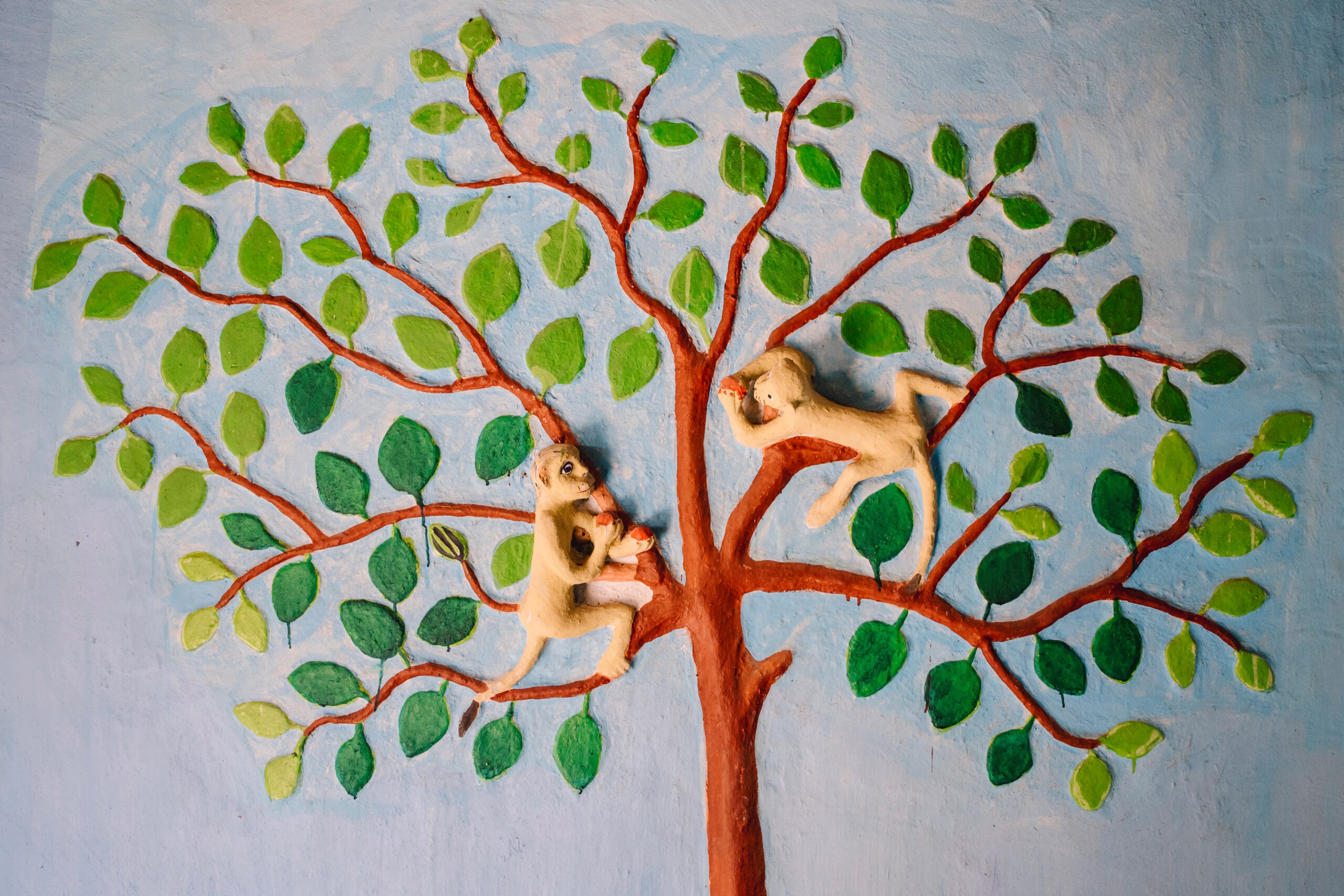Clay relief work on a wall showing monkeys on a tree