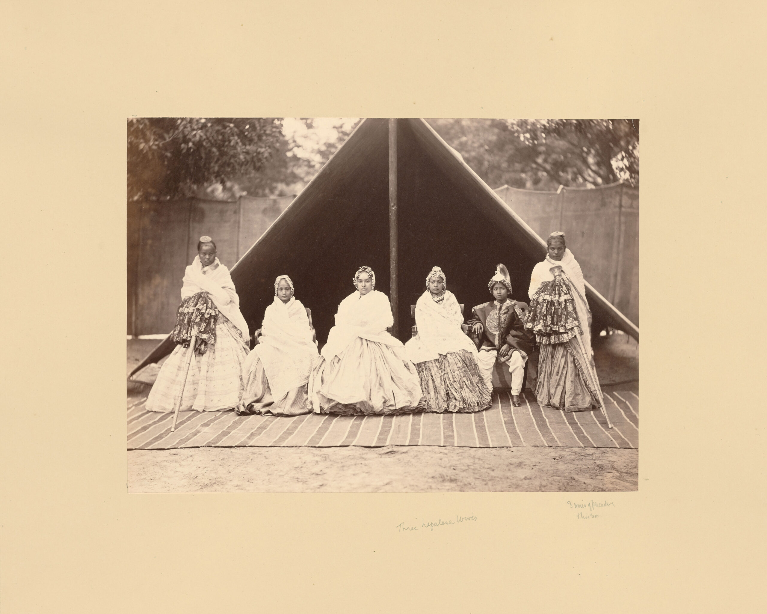 Mid-19th century albumen print of an archival photograph by Bourne & Shepherd showing a group of women and a boy seated in front of a tent in Nepal