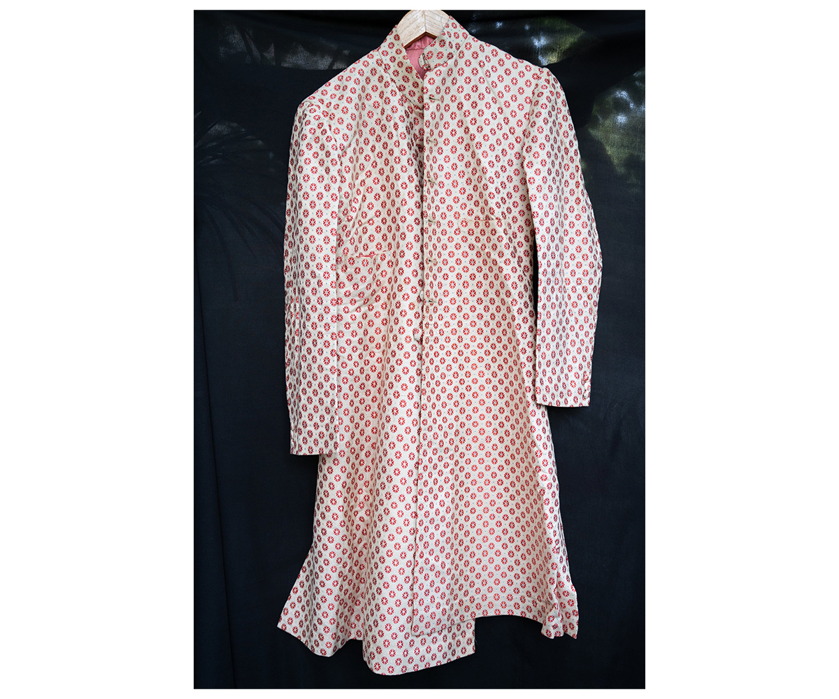 Photograph showing a white silk achkan with red and tiny blue motifs