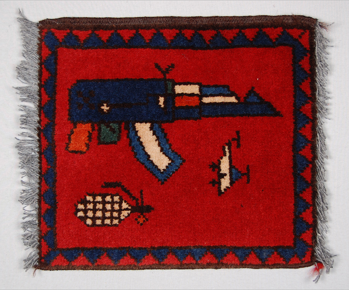 A small square Afghan war mat with plain red ground and blue border with triangles with only 3 stylised objects depicted
