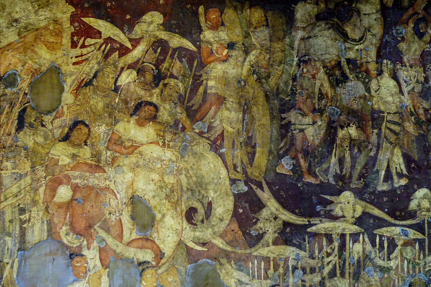 Photograph of a mural in Ajanta Cave 17 showing numerous figures atop elephants and on foot, carrying parasols, spears and banners