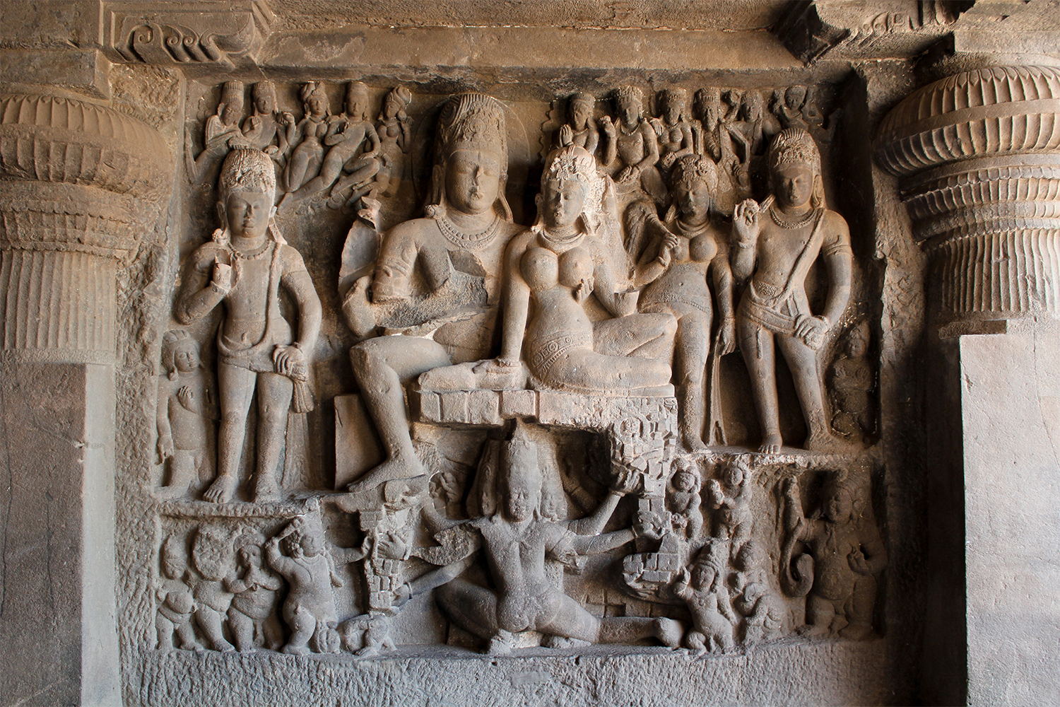 Photograph of a relief panel at Ellora Cave 29, showing Ravana beneath seated Shiva and Parvati in a lifting pose, with many surrounding figures
