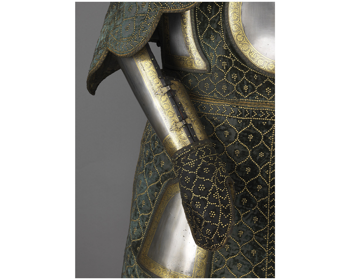 Close-up photograph of different late-17th-century armour parts made up of iron or steel and velvet with gold koftgari