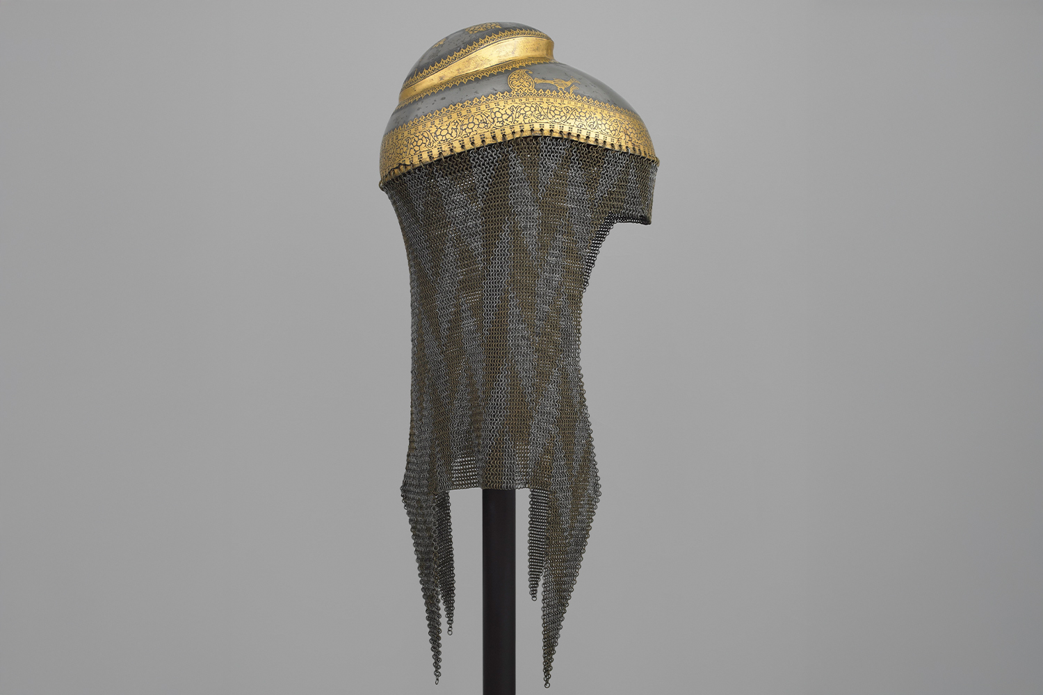 Photograph of a Sikh helmet made of steel with gold koftgari and chainmail