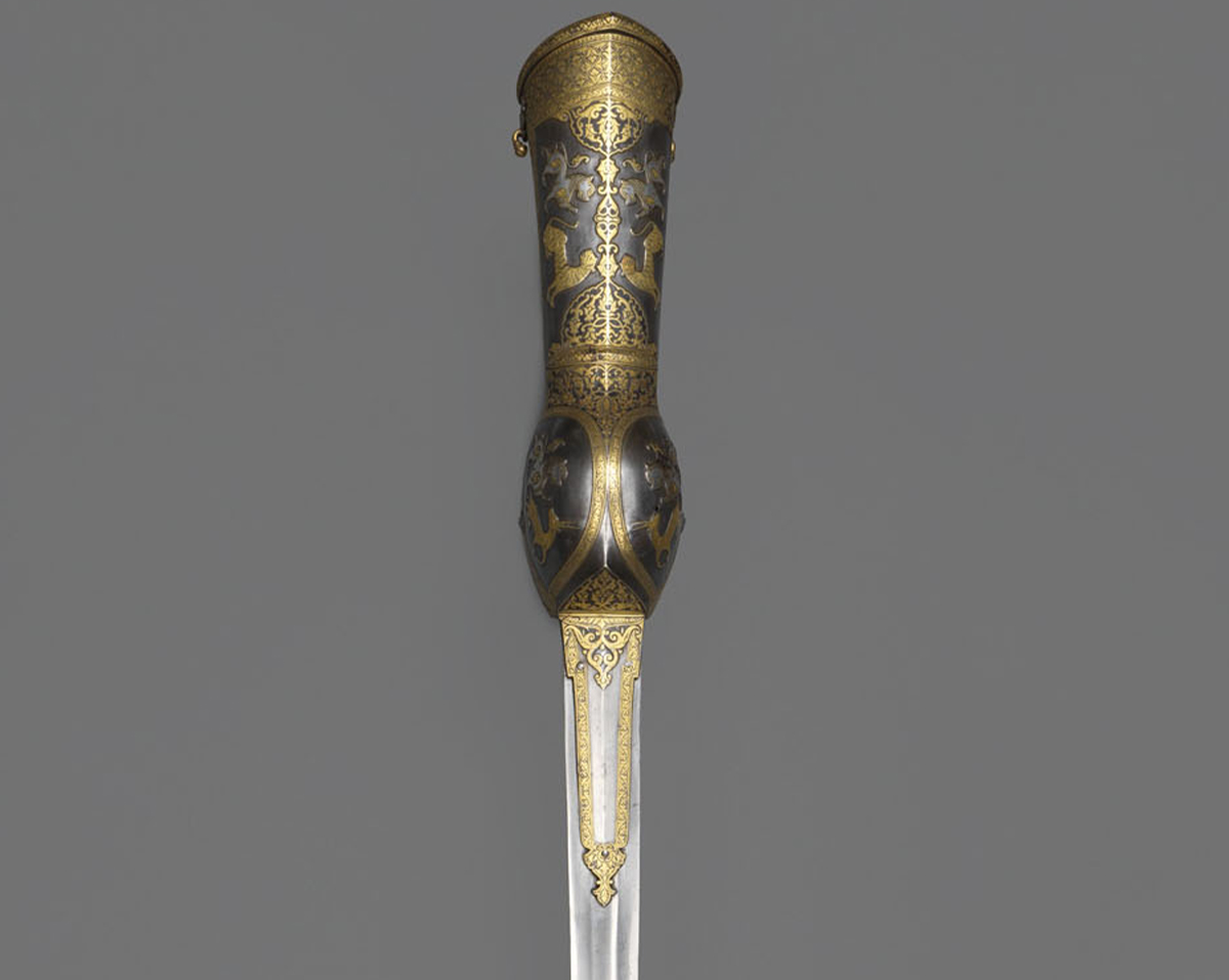 Photograph of a gauntlet sword made of chiselled iron or steel with gold koftgari on its gauntlet