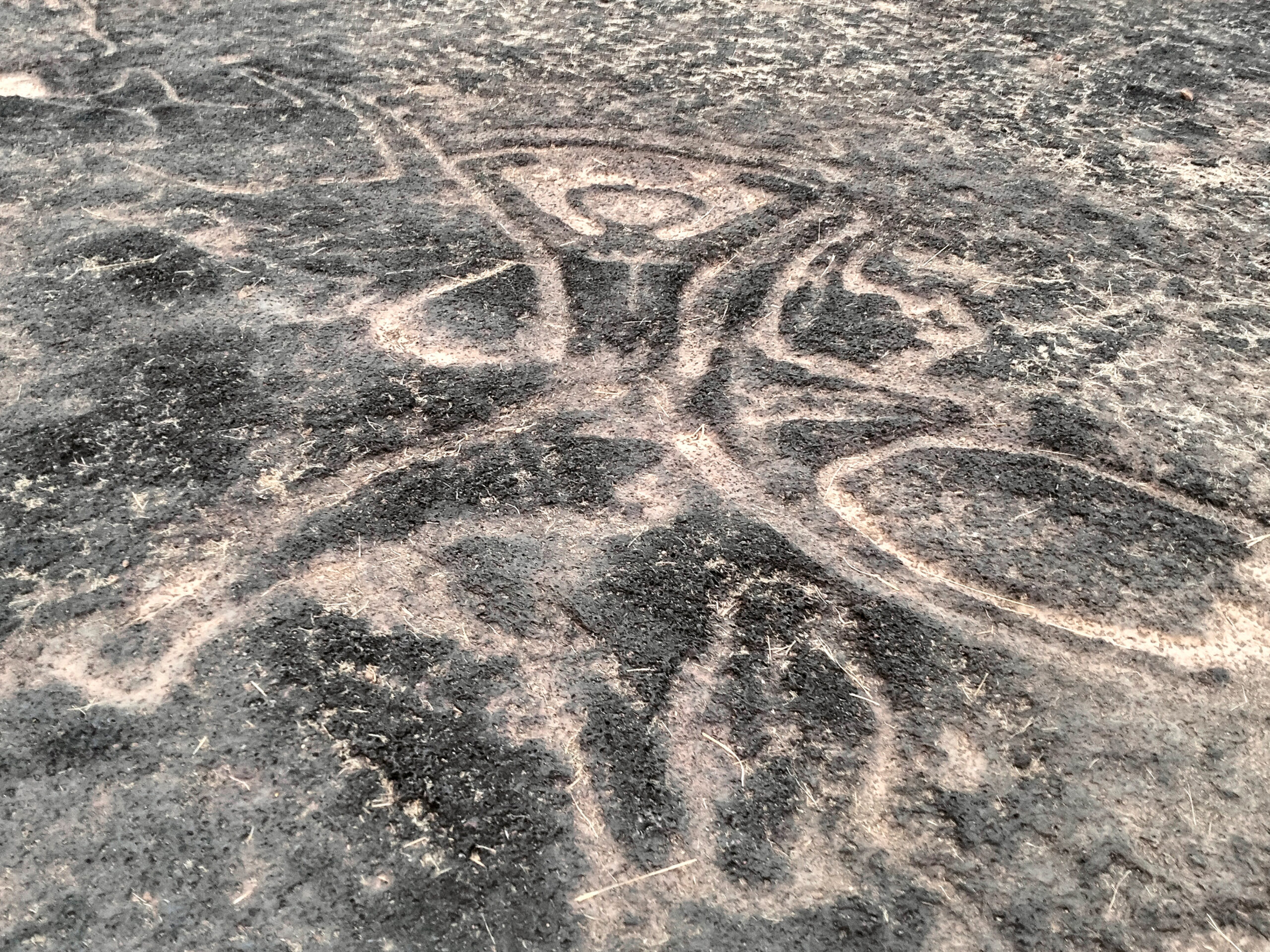 Photograph of a petroglyph showing a human figure with arms extended upwards at Barsu