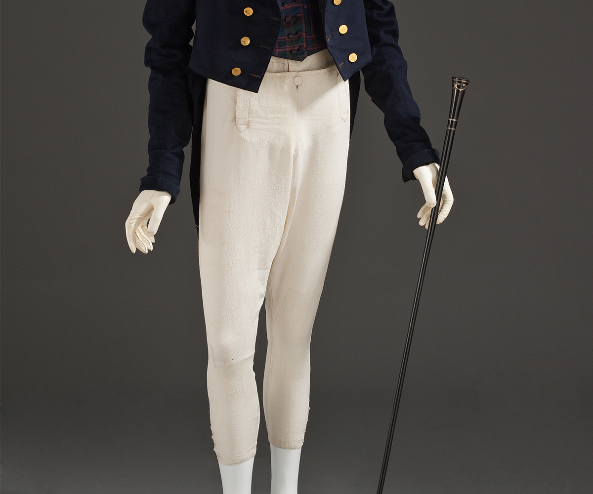 Photograph of a mannequin wearing a top hat, dark navy jacket and white brooches made of silk crepe