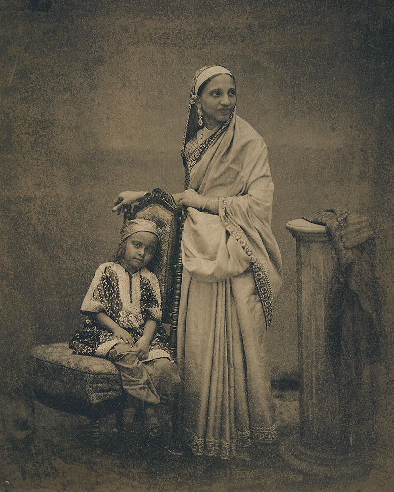 19th-century archival photograph by William Johsnon showing a Parsi lady with a boy seated on a chair