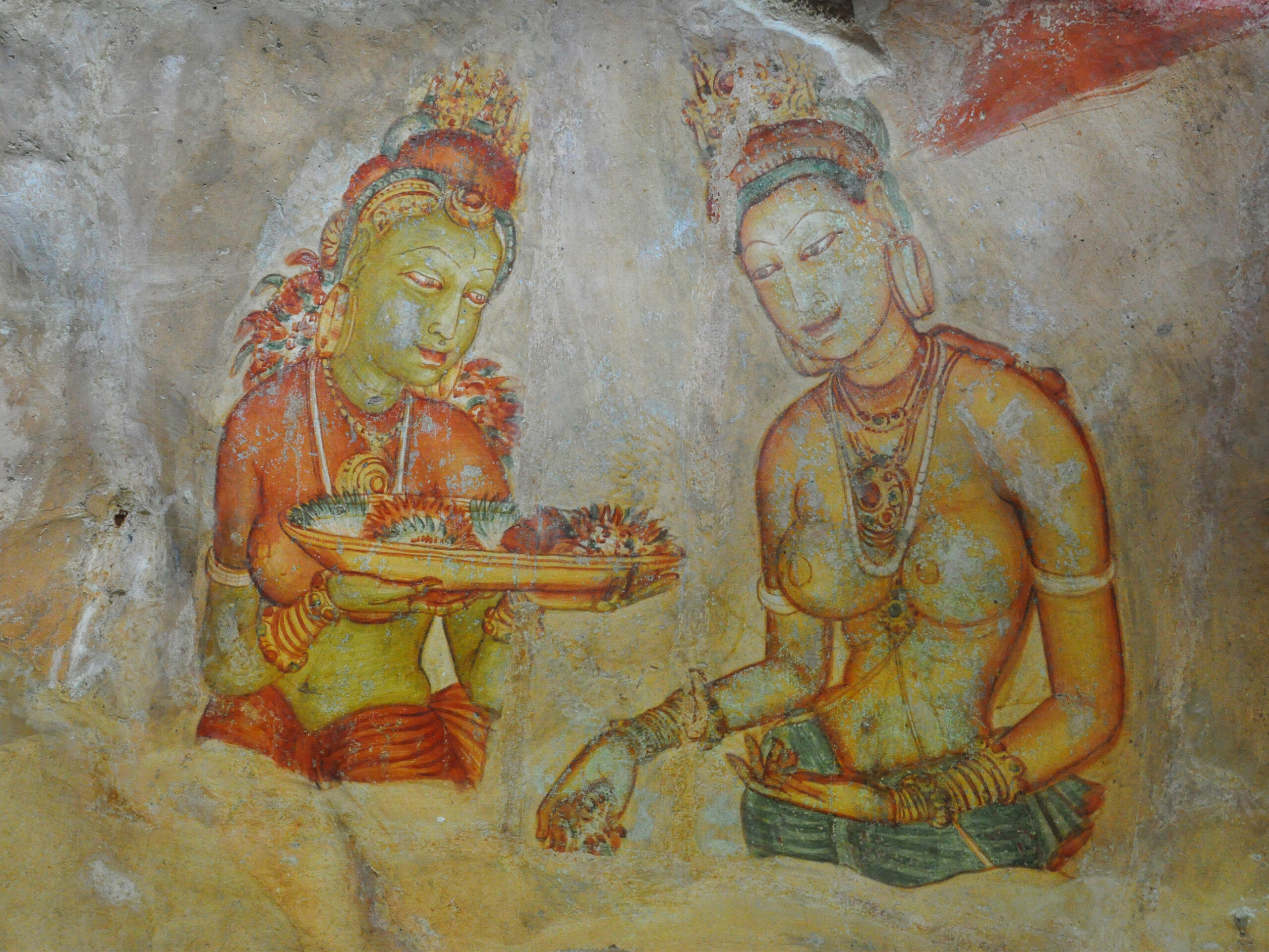 Photograph of a Sigiriya mural showing two women, with one of them holding a tray full of Nil Manel flowers