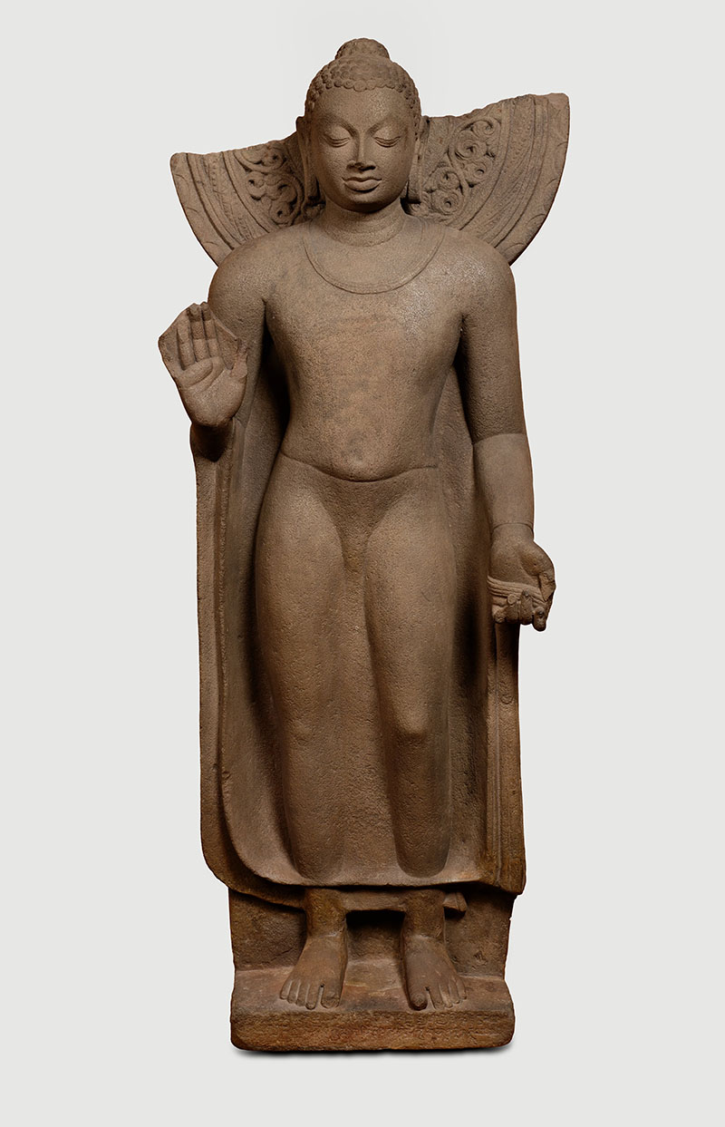 Photograph of a sandstone standing Buddha from the Gupta period with his right hand in the abhaya mudra