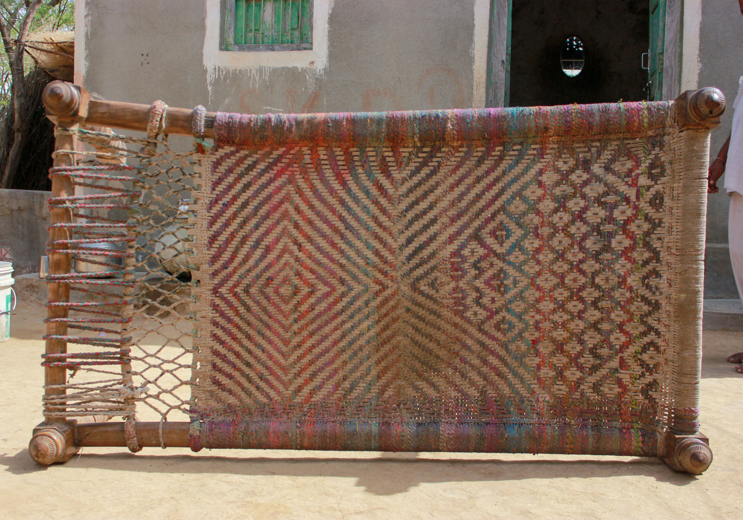 Photograph of a charpoy with its webbing resembling the body and wings of a garuda