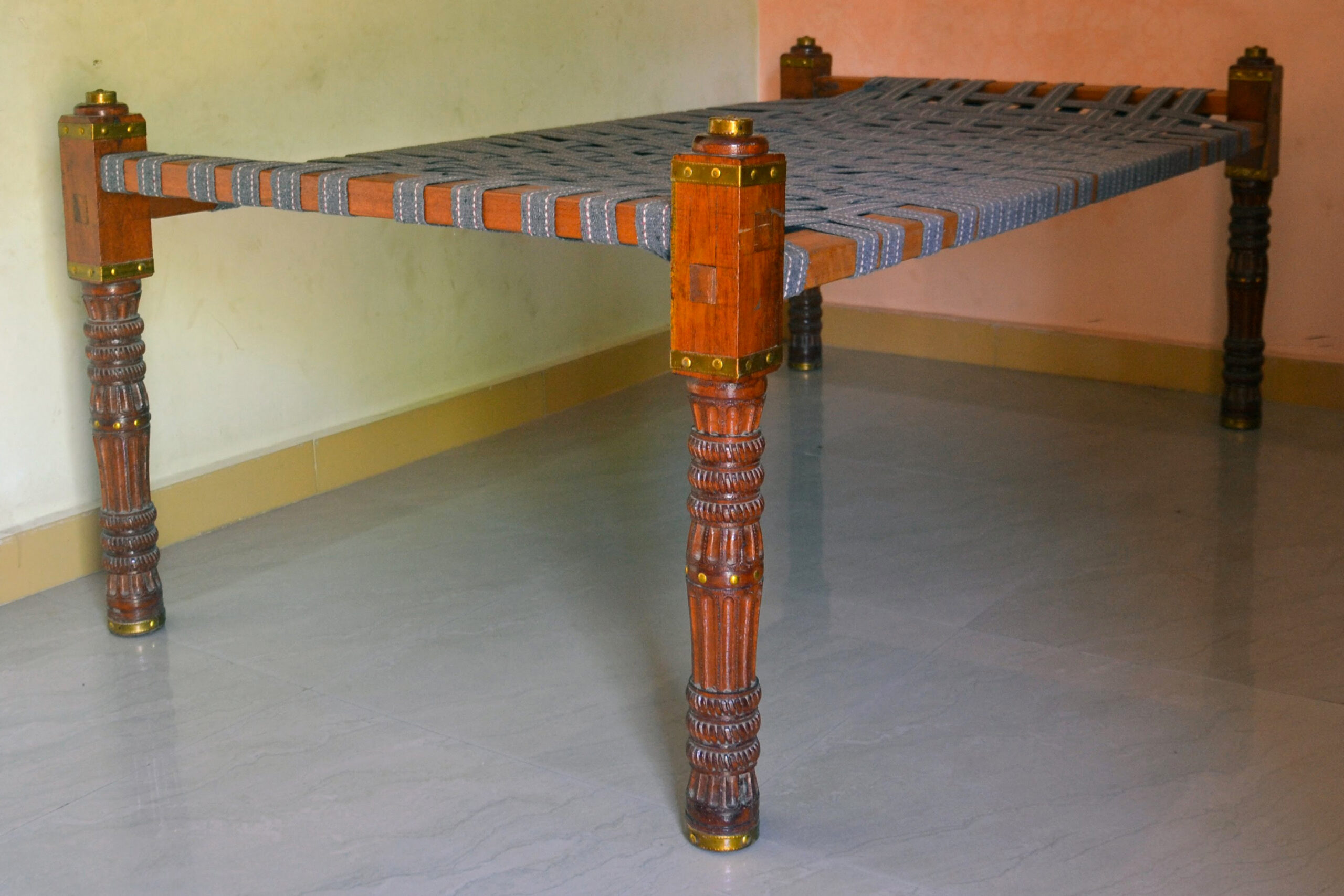 Photograph of a dholni with red lacquered legs featuring traditional carvings