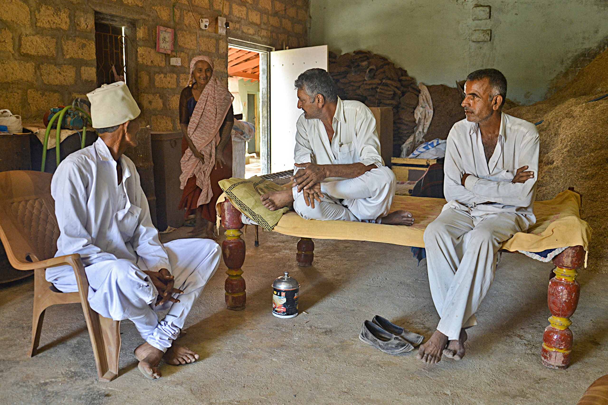 Photograph of the sarpanch (village head) of Kadach, Porbandar, seated on a dholio with another guest