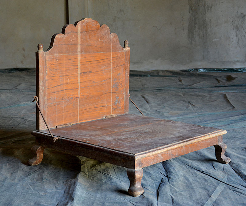 Photograph of a wooden low-seat with backrest called pitha