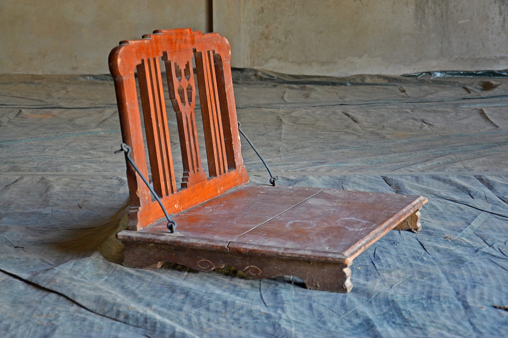 Photograph of a wooden low-seat with backrest called pitha