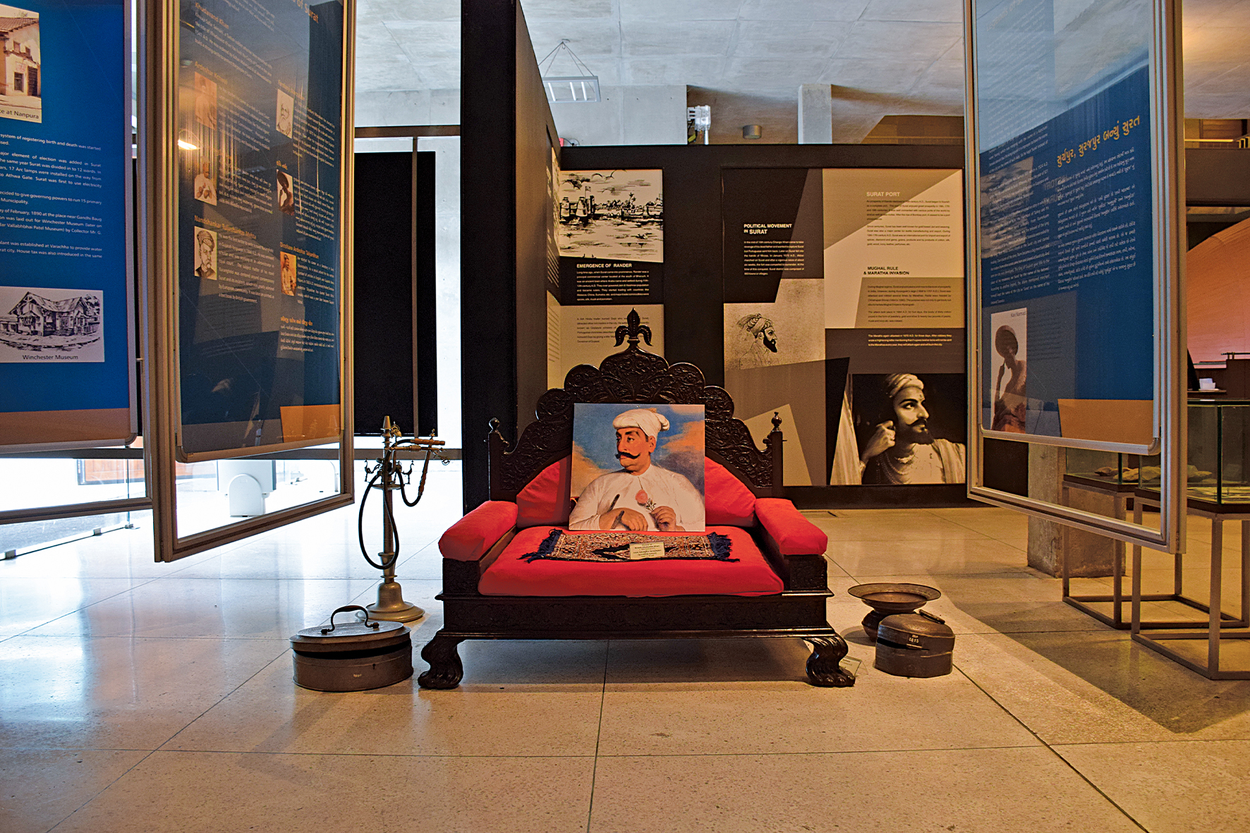 Photograph of a 18th century cushioned low-seat called pitha belonging to the Nawab Afzaluddin Khan with the Nawab's portrait kept on it at the Surat Museum