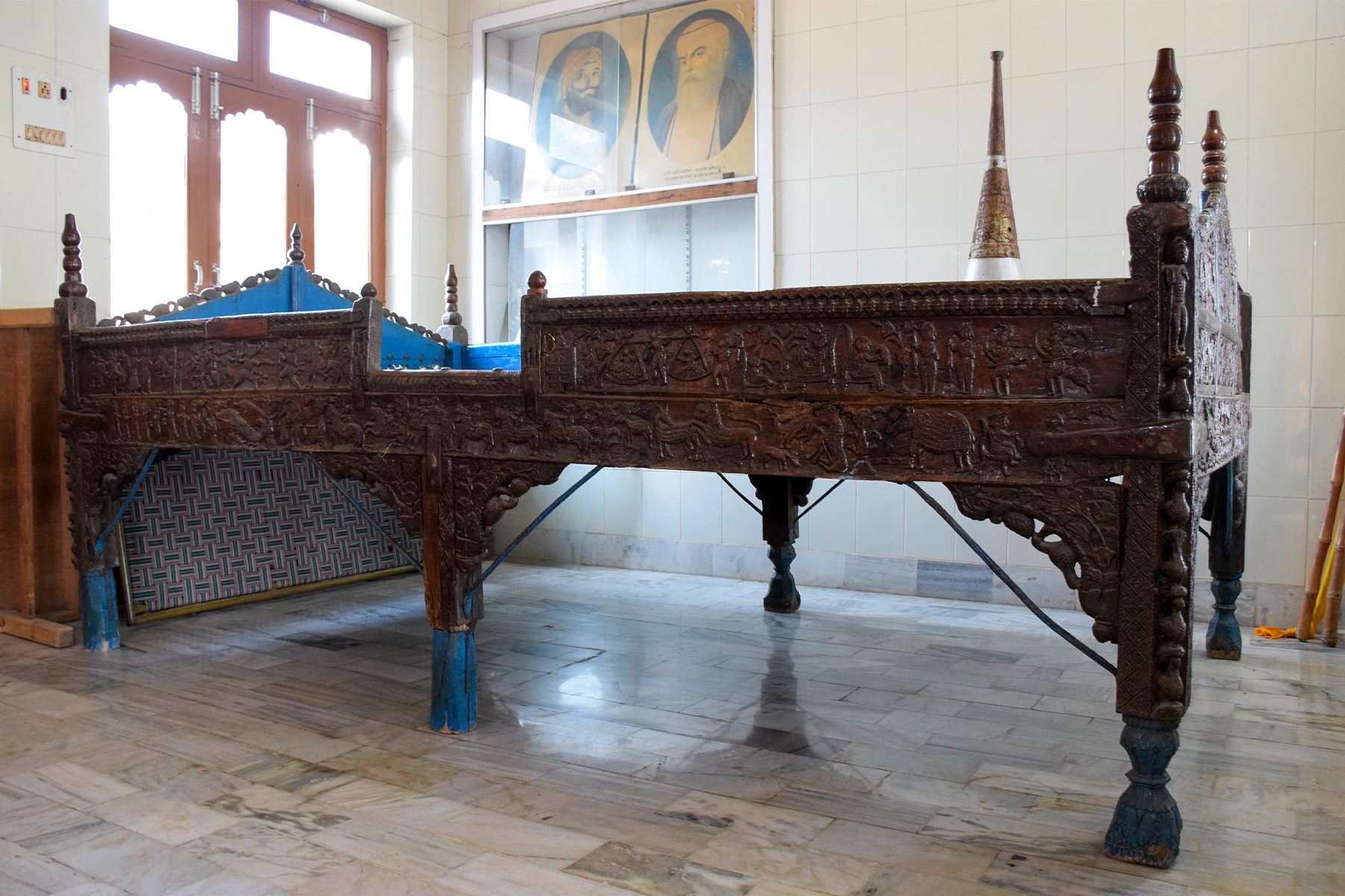 Photograph of a takhat with scenes from the Mahabharata carved on the rails from Punjab
