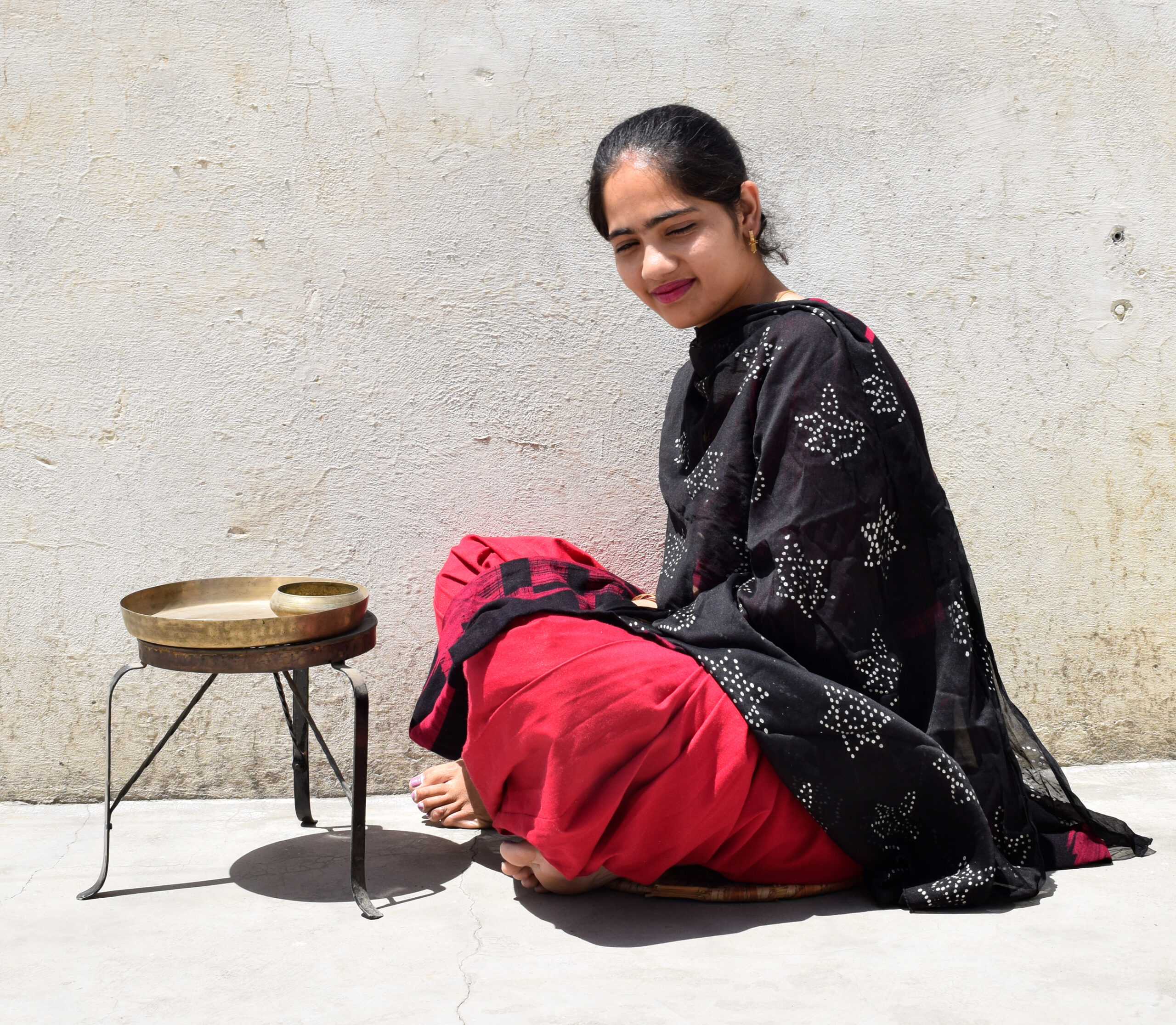 Photograph of a seated woman with a tarpai in front of her used holding a plate