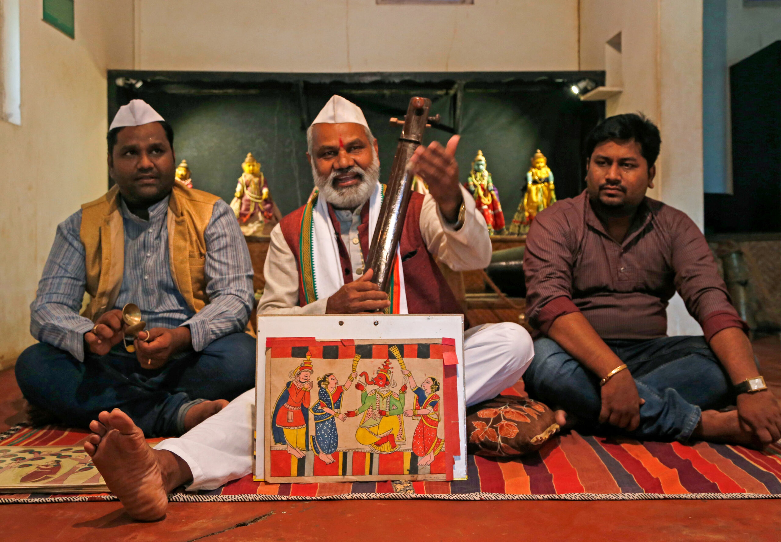 Photograph of three members of the Gangawane family narrating a story with chitrakathi paintings in their museum